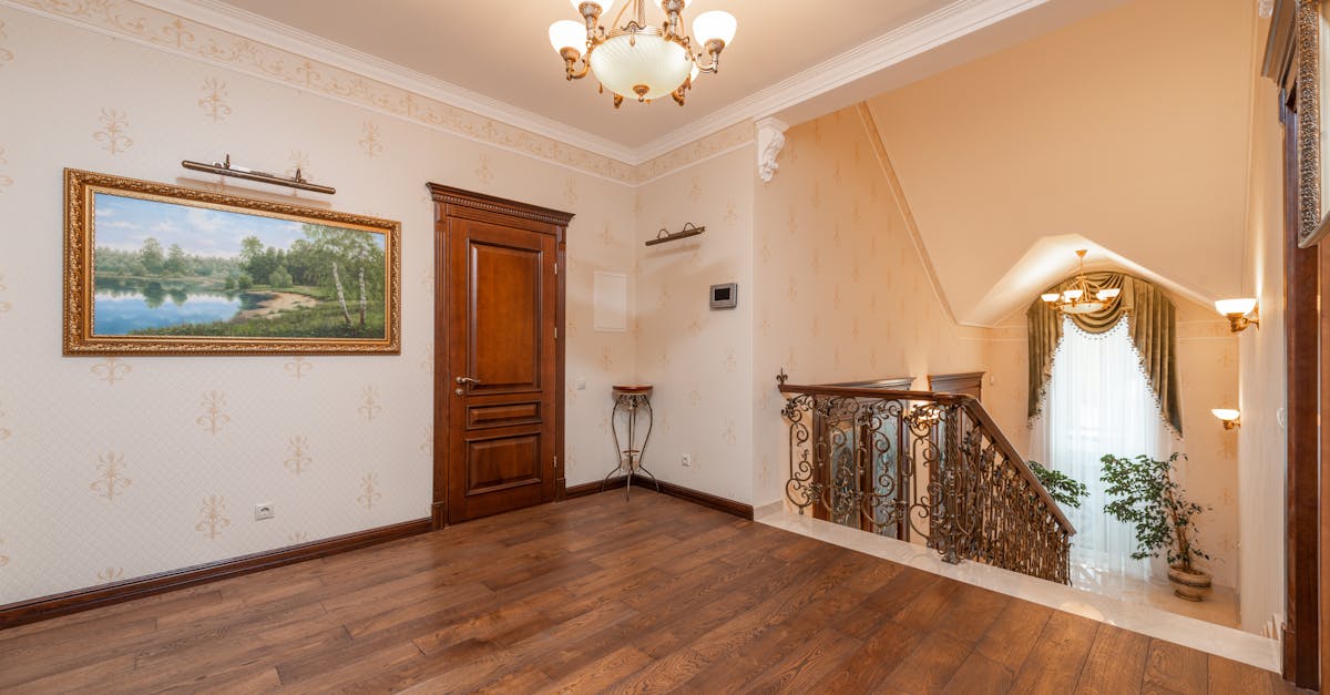 Spacious home interior showcasing elegant staircase, chandelier, and wooden floor.